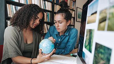 Two young women looking at a globe