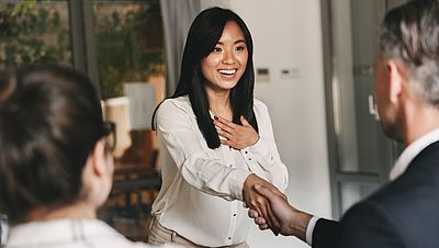 Two business partners in office shaking hand of a young woman