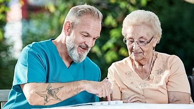 Un cuidador explica la distribución de medicamentos a un anciano