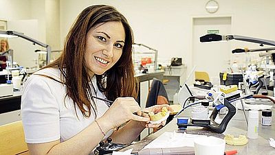 Zahntechnikerin arbeitet an einem Zahnmodell