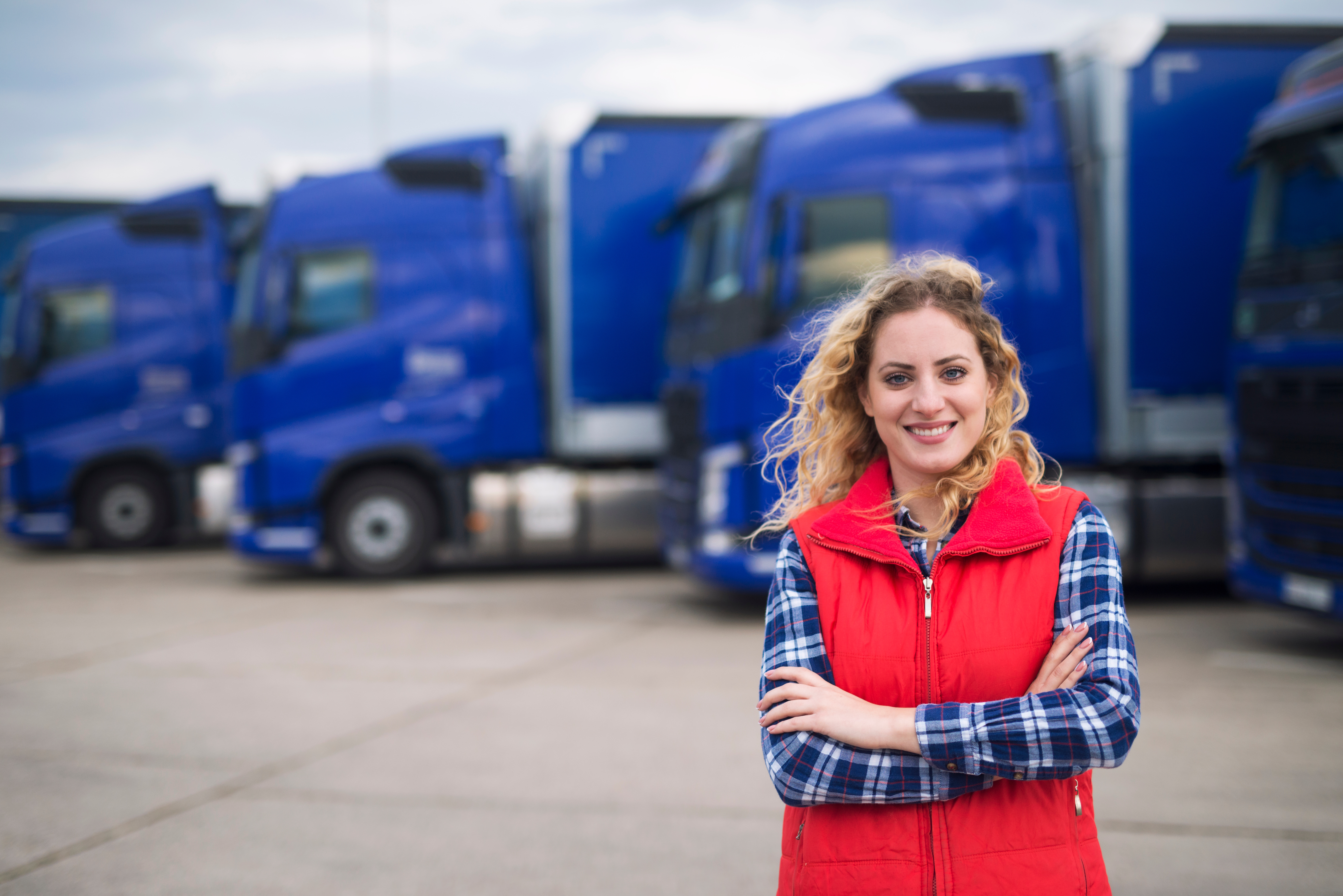 Woman professional driver in front of trucks