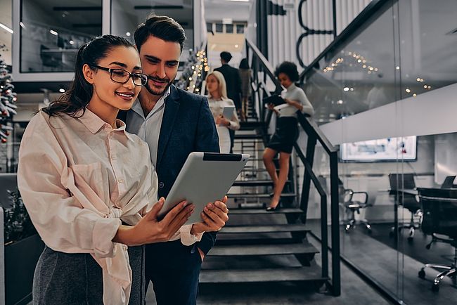 Mann und Frau im Büro schauen auf das Tablet