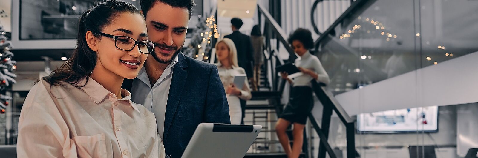 Mann und Frau im Büro schauen auf das Tablet