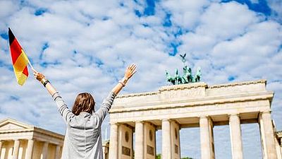 La Puerta de Brandeburgo y una mujer con la bandera de Alemania