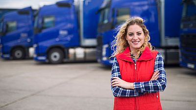 Woman professional driver in front of trucks