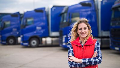 Woman professional driver in front of trucks