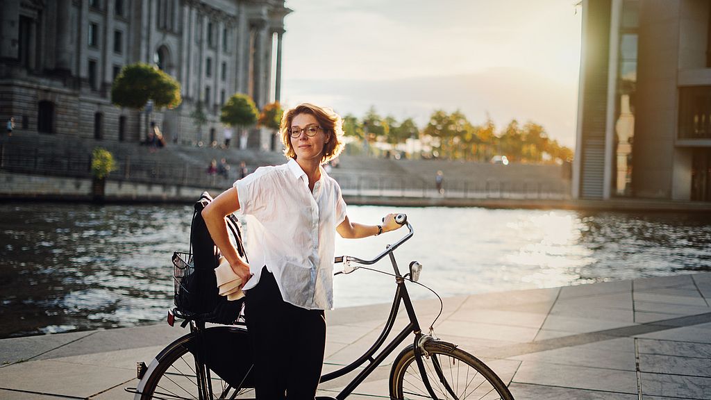 Smiling woman with bicycle in Berlin