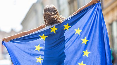 Une jeune femme tient un drapeau de l'UE