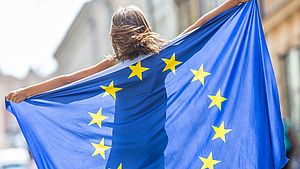 Une jeune femme tient un drapeau de l'UE