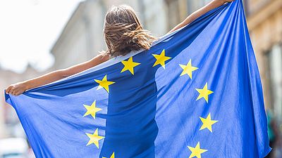 Une jeune femme tient un drapeau de l'UE