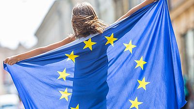 Une jeune femme tient un drapeau de l'UE