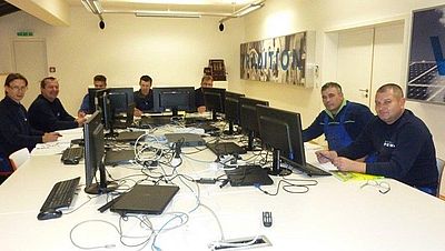 Viele Männer mit Computern an einem Tisch