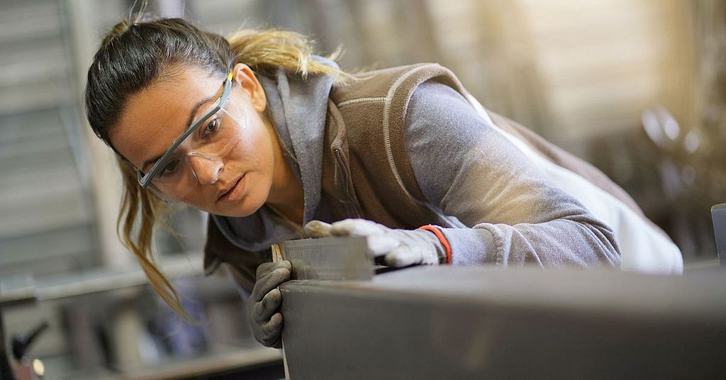 Eine Handwerkerin schneidet Metall