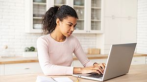 Internationale Frau sucht mit einem Laptop nach Informationen im Internet