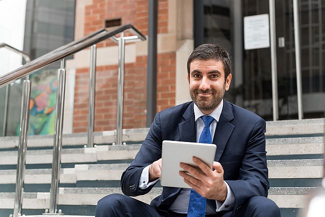 A man in a suit is holding a tablet