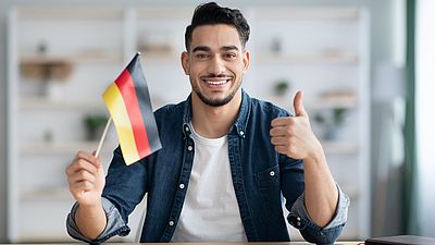 Internationaler lächelnder Mann mit deutscher Flagge