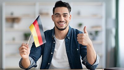 Internationaler lächelnder Mann mit deutscher Flagge