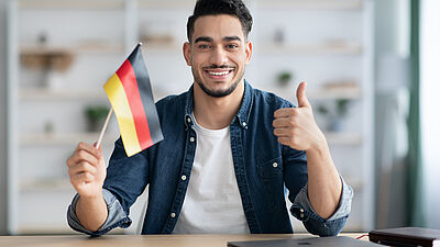 Internationaler lächelnder Mann mit deutscher Flagge