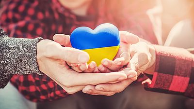 Hände halten ein Herz mit der ukrainischen Flagge