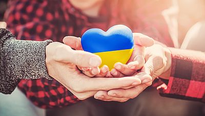 Hands holding a heart with the Ukrainian flag