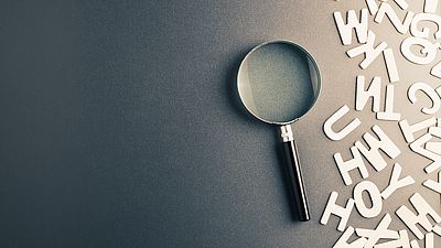 Une loupe et des lettres en papier sur un bureau