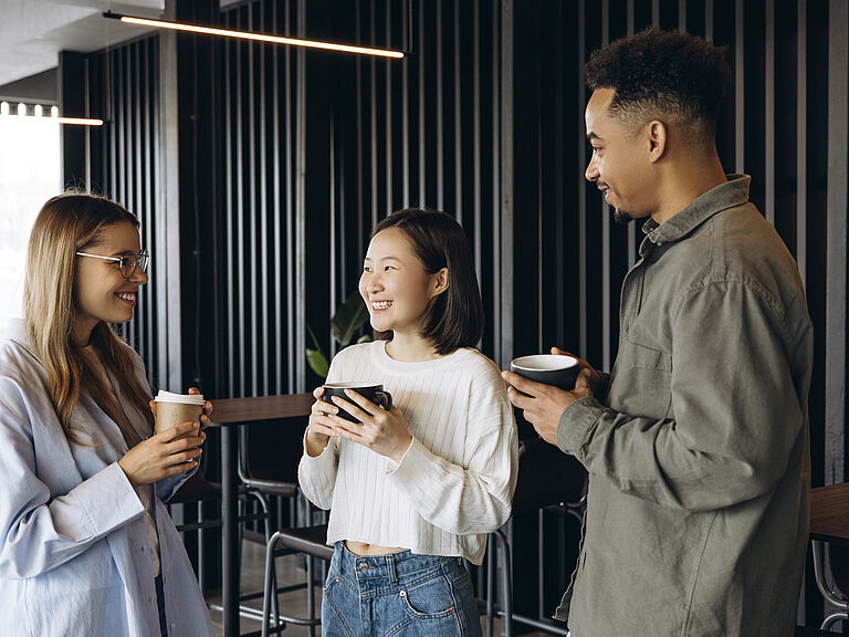 Drei internationale Fachkräfte beim Kaffeetrinken