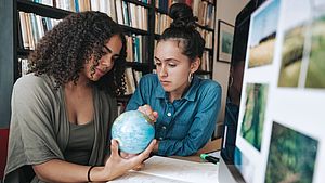 Dos mujeres jovenes observando un globo terraqueo
