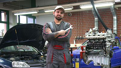 Mann steht vor Auto mit offener Motorhaube