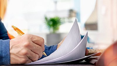 Hand einer Person, die ein Visumantragsformular ausfüllt