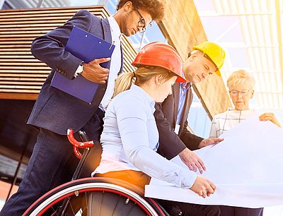 Femme en fauteuil roulant avec des collègues lors de la planification de la construction