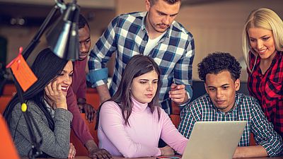 Multicultural group of men and women share ideas around a computer