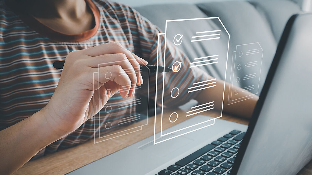 Persona marca una lista de verificación virtual que flota sobre un portátil.